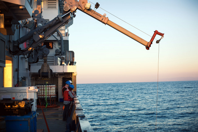 Deploying an instrument to measure the way light interacts with seawater. Credit: Gad Girling